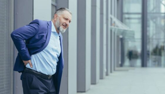 Overtired senior gray-haired man outside office building, businessman in business suit