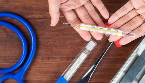 Hands Exchanging a Thermometer in a Medical Setting