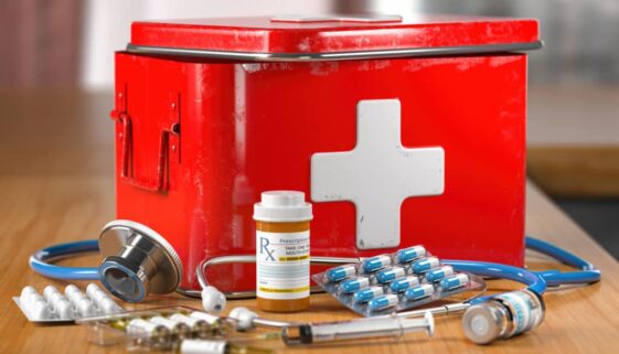 Open first aid kit with stethoscope, pills and smedicationon the