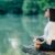 Frau sitzt am See und meditiert